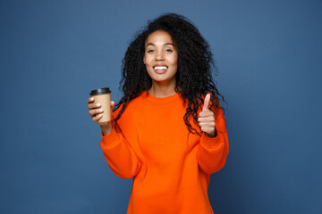 Cheerful young african american woman in casual basic bright orange sweatshirt standing hold paper...