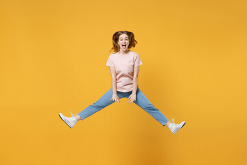 Fototapeta na wymiar Full length of young overjoyed expressive surprised shocked woman 20s wearing casual basic pastel pink t-shirt jumping highwith outstretched legs isolated on yellow color background studio portrait.
