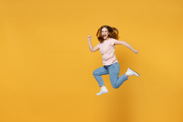 Full length of young sportive energetic caucasian hurrying up woman 20s wearing basic pastel pink t-shirt jumping high runnig fast look camera isolated on yellow color background studio portrait.