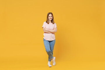 Fototapeta na wymiar Full length of young confident smiling student woman 20s wear casual basic pastel pink t-shirt, jeans looking camera, holding hands crossed folded isolated on yellow color background studio portrait.