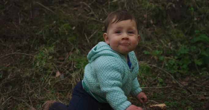 A little baby is playing outdoors in the garden on a winter day