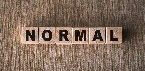 NORMAL word written on wooden blocks on a brown background.