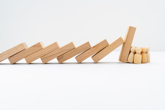 Group Of Wooden Peg Dolls Resisting And Stopping Domino Effect Falls.