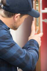 Naklejka na ściany i meble man is using a screwdriver to adjust a door hinge