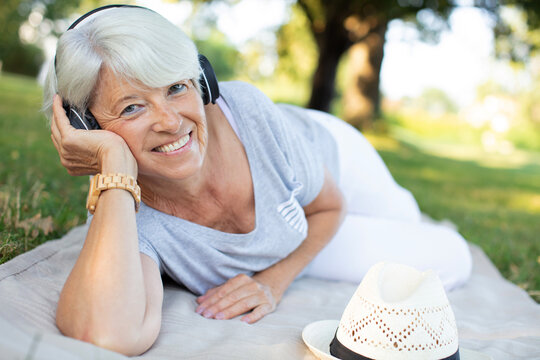 beautiful smiling senior woman listening to music in park