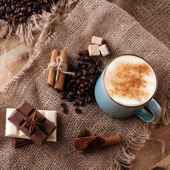 cup of coffee with cinnamon, anise chocolate on wooden background view above 