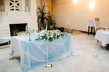 The presidium of the newlyweds in the banquet hall of the restaurant is decorated with candles and green plants