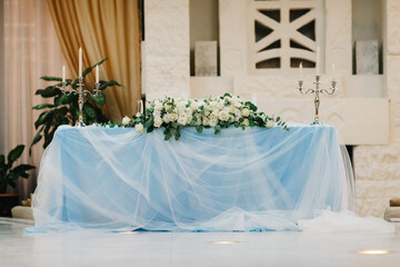 The presidium of the newlyweds in the banquet hall of the restaurant is decorated with candles and green plants