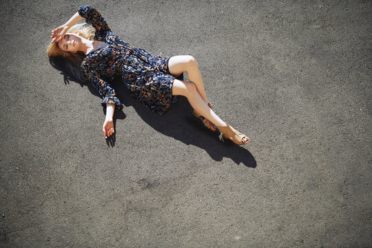Seductive woman lying on road during sunny day