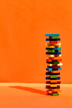 Tower of colorful construction blocks against orange background