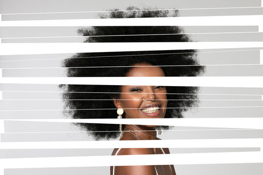Smiling Afro woman with digital stripes on face against white background