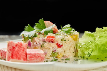 Appetizing salad from crab sticks with rice and vegetables on wooden table.