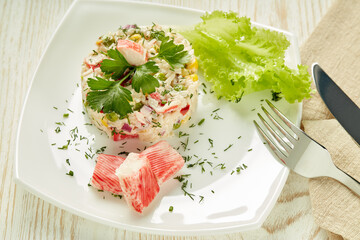 Appetizing salad from crab sticks with rice and vegetables on light wooden table. Top view
