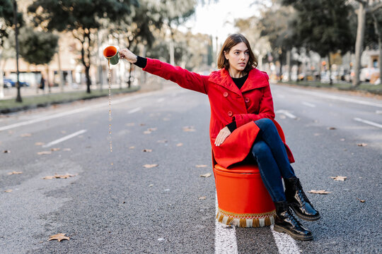 Young woman with attitude spilling coffee from cup on street