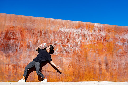 Man looking at face mask while standing against wall