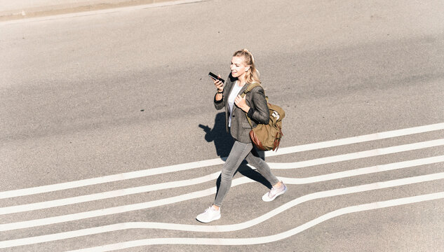 Young woman talking through smart phone while walking on street during sunny day