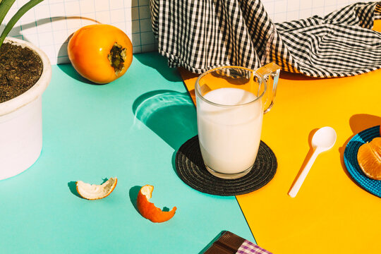 Milk cup by napkin and fruit on multi colored table