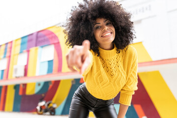 Smiling woman pointing finger while standing outdoors