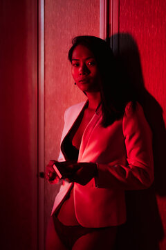 Sensual woman holding matchbox while standing in low red light at home