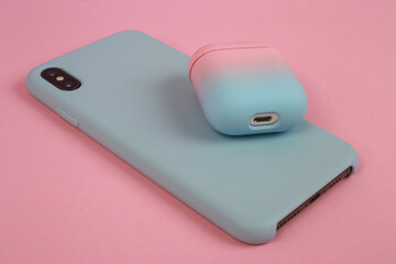 Phone in a case and a case for headphones on a pink background. Stylish phone and headphone case. Woman devices