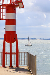 Rot weißer Leuchtturm auf dem Nolledijk in Vlissingen, im Hintergrund das Meer mit einem Segelboot, Zeeland, Walcheren, Holland
