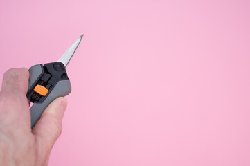 Person holding gardening pruning shears against a pink background - copy space