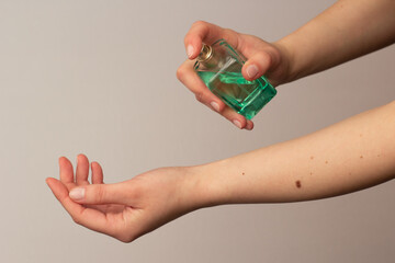 Closeup of a woman spraying perfume on her wrist.