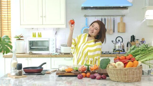 Asian woman Happy with the new kitchen, dancing, expressing joy with a smiling face at home.