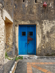 Fototapeta na wymiar closed blue door of an old building or house with a fragment of the floor, exit to the courtyard or street, a fragment of the facade