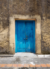 closed blue door of an old building or house with a fragment of the floor, exit to the courtyard or street, a fragment of the facade