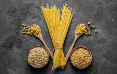 Various raw pasta on stone background, uncooked food concept