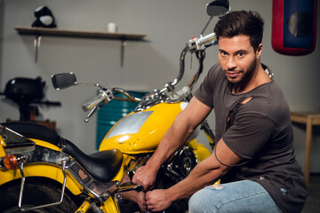 A modern young man in a t-shirt and jeans is engaged in bike diagnostics in a repair shop or garage