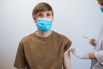 Male getting Covid-19 vaccine. Close up doctor making injection to patient in medical mask. Syringe of coronavirus vaccine. Man receives jab vaccinated. Pacents gets a flu shot. Inject in arm