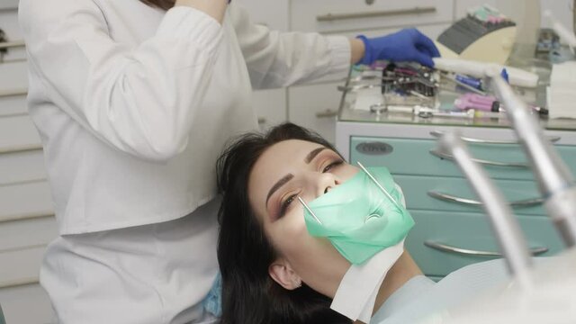 The doctor dentist woman treats teeth with a drill to a patient. Dental clinic 4K