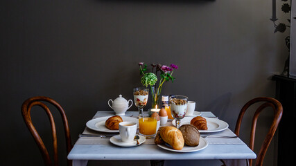 Breakfast table with a continental breakfast for two people against a grey wall