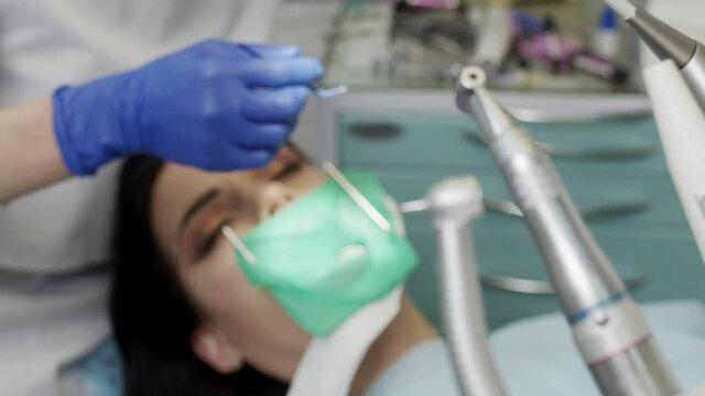 The doctor dentist woman treats teeth with a drill to a patient. Dental clinic 4K