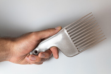 Hand holding a brown hair comb over a white background