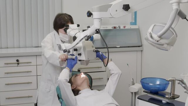 Little doctor child welcomes the patient and makes diagnosis with a microscope 4K. Medicine covid 19