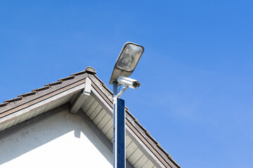 white solar powered surveillance camera in front of a house facade, constant surveillance is a...