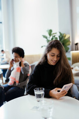 Portrait of female student using net-book while sitting in cafe