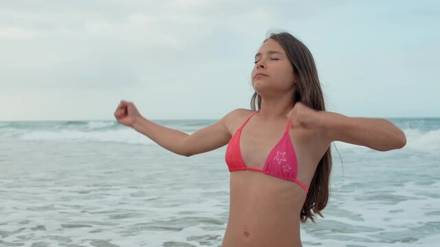 Young woman enjoying summer at seaside. Girl doing exercises at coastline.