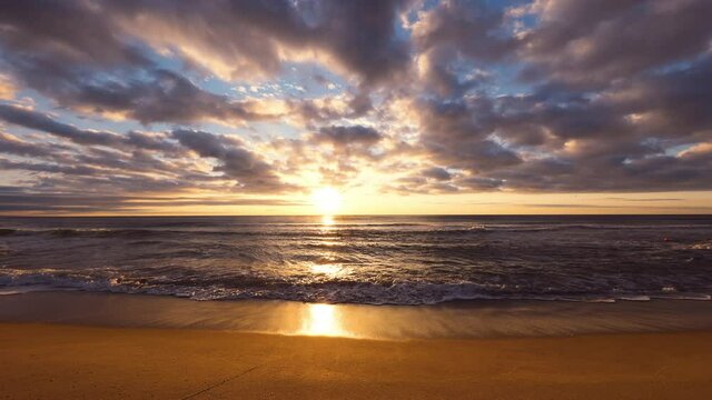 Sea sunrise and splashing waves on the sand