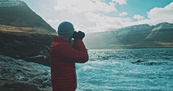 Man taking pictures of the waves in a winter scenery. 