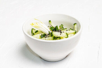 Fresh cucumber salad with sesame seeds in a white ceramic bowl