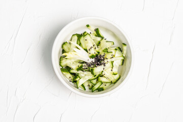 Fresh cucumber salad with sesame seeds in a white ceramic bowl