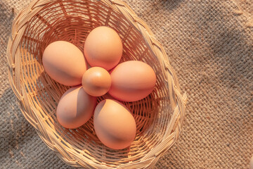 small fresh eggs surround by common eggs size in a wooden basket from agriculture farm.