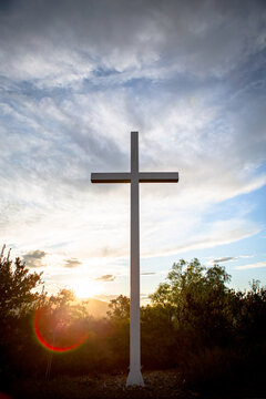 Sunlight bursts behind a mountain top cross of Jesus during golden hour at sunrise on Easter Morning 02