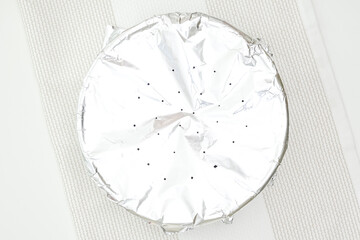 Baking pan covered with aluminum foil close up on kitchen table. Step by step cake recipe