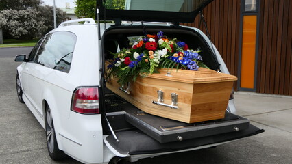 closeup shot of a funeral casket in a hearse or chapel or burial at cemetery
