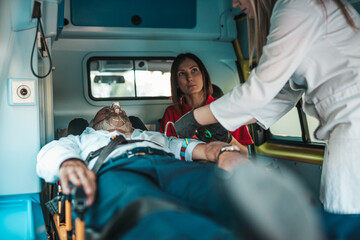 Emergency medical service at work. Paramedic is pulling stretcher with senior man with serious heart attack to the ambulance car. Help on the road. Drivers assistance concept. © hedgehog94